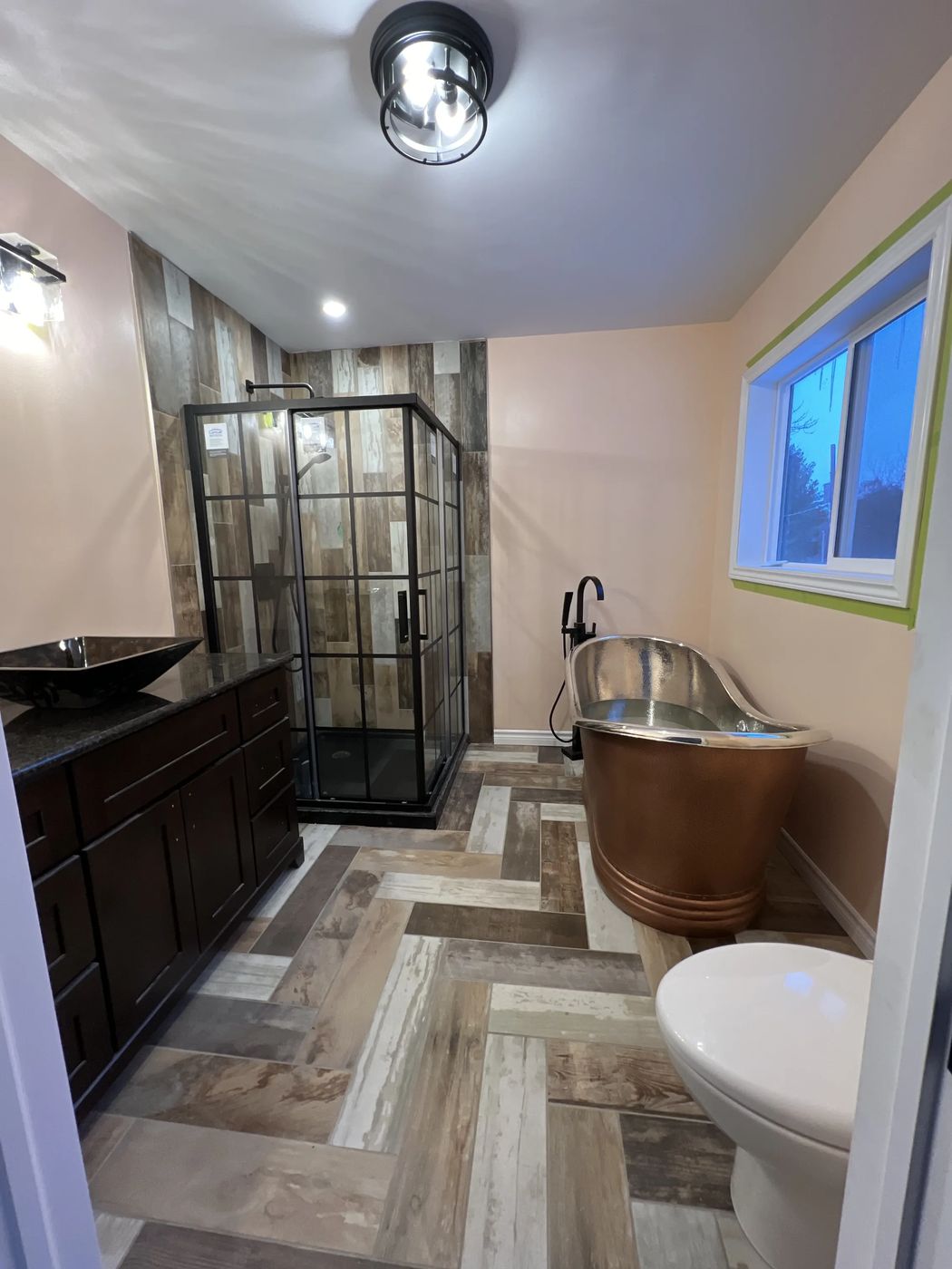 Bathroom renovation with copper soaker tub and herringbone tile floor